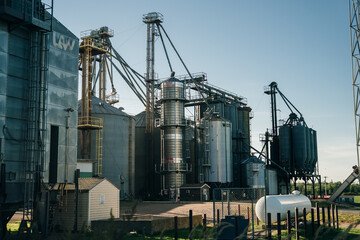 Modern Granary elevator. Silver silos on agro-processing and manufacturing plant for processing drying cleaning and storage of agricultural products, flour, cereals and grain.