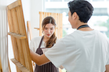 Fototapeta premium Closeup shot of Asian professional cheerful happy female carpenter worker staff in apron smiling talking discussing choosing color chart pattern from male lover couple in home building workshop