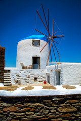 White windmill with blue rooftop in a blue sky in Greece - 615991276