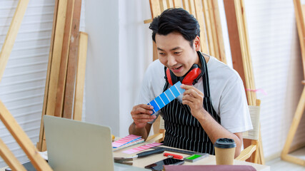 Asian professional cheerful happy male carpenter worker staff in apron with earphones sitting...