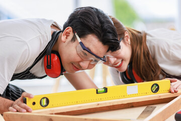 Asian professional skilled male carpenter worker staff in apron with earphones and safety goggles...