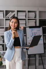 Businesswoman is analyzing strategy of new business project and working on laptop in modern office