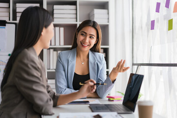 Fototapeta premium Two businesswomen working on laptop to discussion and brainstorming about strategy of new business