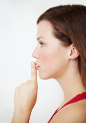 Secret, hand and woman with finger on lips in studio for gossip, privacy or sign on white background. Whisper, profile and female person with silence, confidential or emoji with drama or announcement