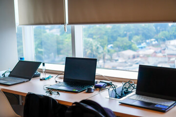 Row of laptops resting on office desk in front of window after work hours