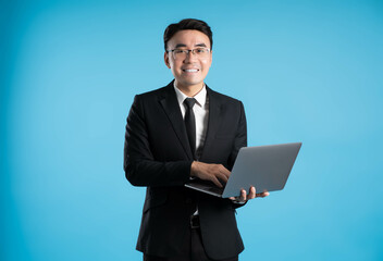 image of asian business man using laptop on blue background.