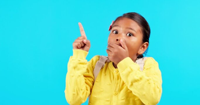 Hand pointing, face and wow by girl child in studio with surprise announcement on blue background. Omg, news and kid portrait with shocked, emoji or finger showing promotion, deal or coming soon sale