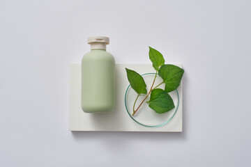 Rectangle podium with a pastel cosmetic bottle and a petri dish of fish mint leaves. Gentle skin...