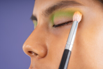 Making up the eyelid of the young woman with green color