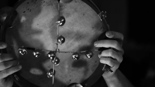 Two hands waving an old tambourine close-up, black and white video