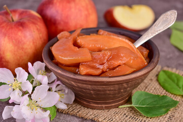 Apple jam in a clay bowl and fresh apples. Close-up.
