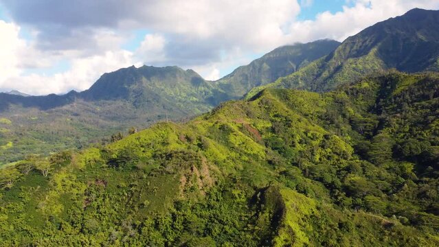 Cinematic Aerial shot of Hanalei Bay and green mountains with a waterfall  in Kauai, Hawaii.