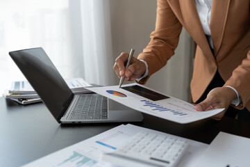 Businesswoman analyzing income charts and graphs with laptop computer. business analysis and strategy concept Business statistics, profit, financial growth rate on graph paper. financial data chart