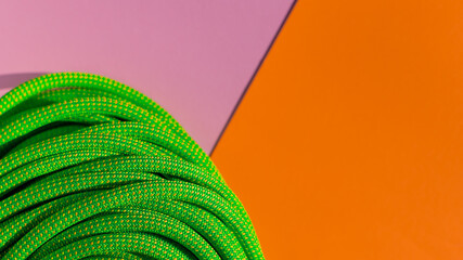 green rope for rock climbing and mountaineering lies on a colored background. background image of...