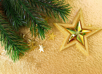 Close up red ornament and gold star hanging from branch of Christmas tree