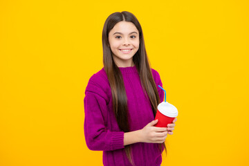 Teenager girl holding a hot cup of coffee or tea. Child with takeaway cup on yellow background, morning energy drink beverage.