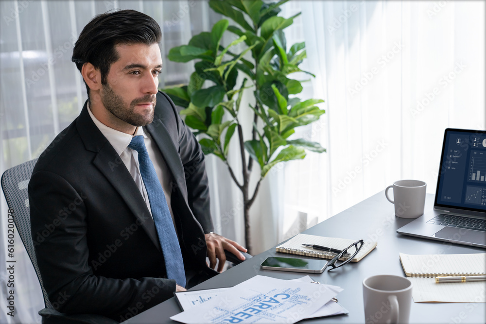 Poster modern professional businessman at modern office desk using laptop to work and write notes. diligent