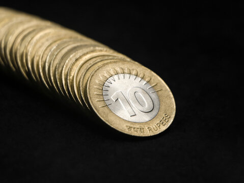 closeup shot of rare vintage indian bimetallic 10 (ten) rupee coin in gold and silver arranged in a straight row isolated in a black background