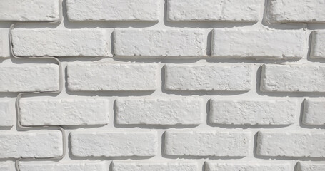 White brick wall background, close-up shot, on the left side there is a white wire running along the line of the brick according to the architect's principles of interior and exterior decoration.