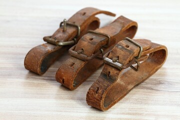 Old leather straps used to tei up skis togetner. Natural leather belts on wooden table.