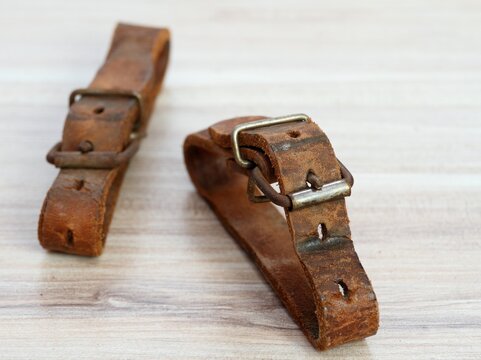 Old leather straps used to tei up skis togetner. Natural leather belts on wooden table.
