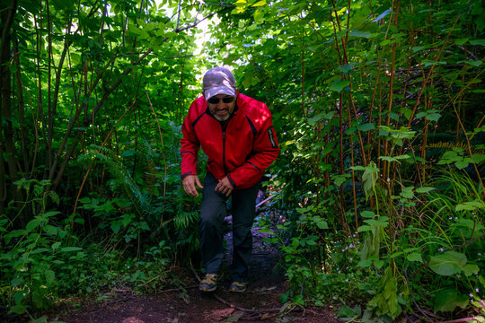 Adventurous athletic man acting funny as he walks out of the bushes covering a hiking trail on the rugged coastline of the Pacific Northwest.
 - Powered by Adobe
