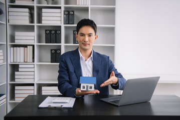 Asian man working with House model real estate agent and customer discussing for contract to buy house, insurance or loan real estate consult concerning mortgage loan offer