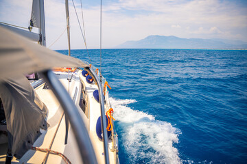 Yacht sailing in an open sea. Close-up view of side of the boat. Clear sky after the rain, waves and water splashes