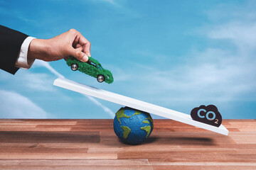 Businessman weighs eco-friendly EV car on scale against CO2 symbol, promoting corporate...