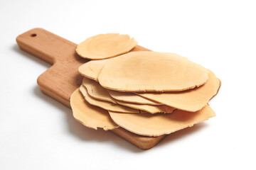 Drid and sliced tongkat-ali (long jack) on chopping board, isolated on white background. (side view)