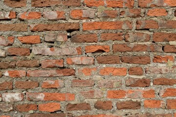 Old red brick wall with peeling plaster