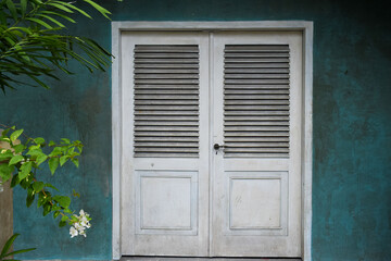 Green wall with ancient windows in bone white.
