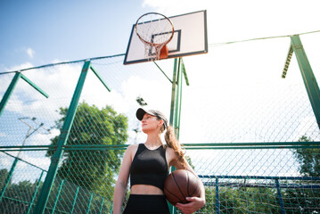 Young sports girl with a basketball on the basketball court outdoors,
