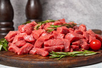 Raw beef meat chopped in cubes. Diced beef or lamb on a wooden serving board