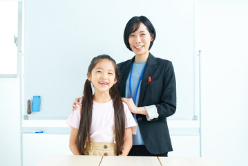 ホワイトボードの前に並ぶ女の子とスーツ姿の女性