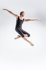 Fototapeta na wymiar Ballet Dancer Young Caucasian Athletic Man in Black Suit Dancing in Studio Over White Background With Lifted Hands.