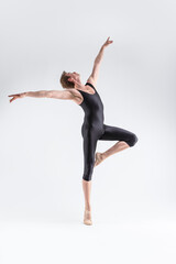 Fototapeta premium Caucasian Ballet Dancer Young Caucasian Athletic Man in Black Suit Posing Flying Dancing in Studio On White With Lifted Hands.