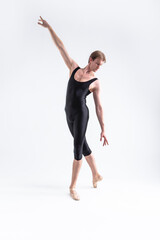 Fototapeta na wymiar Sports Concepts. Athletic Caucasian Dancing Ballet Man Posing in Stretching Pose with Lifted Hand in Black Tights On White.