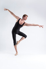 Fototapeta na wymiar Professional Male Ballet Dancer Young Man in Black Dance Tights Suit Posing in Ballanced Dance Pose in Studio.
