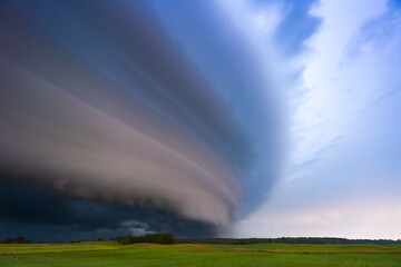 Naklejka na ściany i meble Angry supercell storm influenced by Climate change. Dangerous storm supercell shelf cloud with layers.