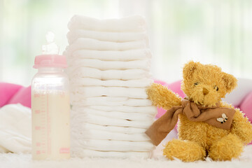A little teddy bear and stack of disposable diapers