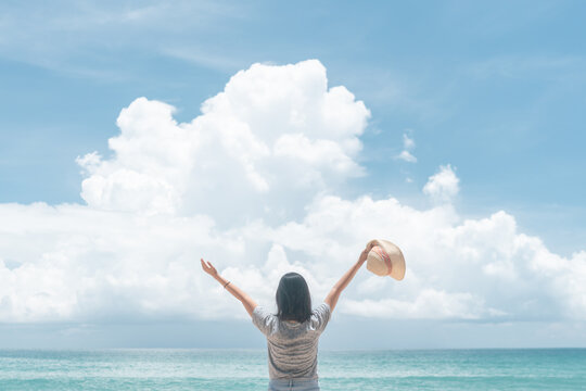 Young woman rise hand up to sky feel relax and free with summer beach background.