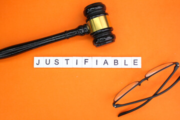 judge's gavel and glasses with the word justifiable. concepts can be justified. there is truth - obrazy, fototapety, plakaty