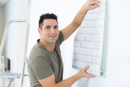 male smearing wallpaper with glue