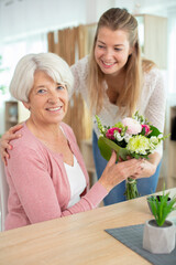 daughter offering freshly cut flowers to her mature mother