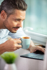 smiling modern young man using gadgets at cafe