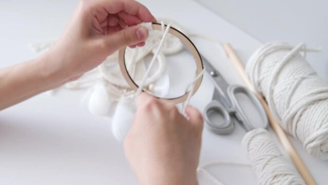 Macrame. The girl weaves macrame. White thread, female hand, close-up