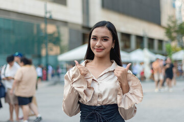 A pretty asian woman standing outside wearing a light tan silk blouse and a high waist skirt,...