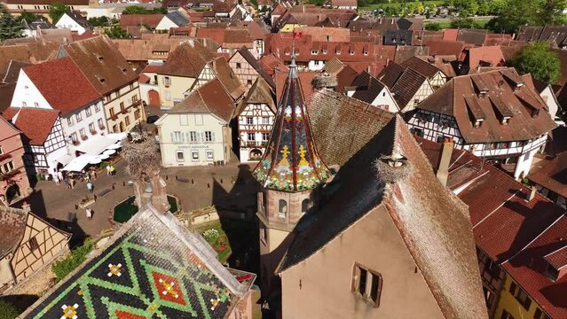 Aerial Drone Shot of Eguisheim village in the Alsace province, France. Picturesque Church with storks at Sunny Day
