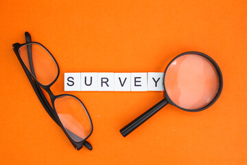 magnifying glass with the word survey alphabet letters. the concept of surveying or analyzing...